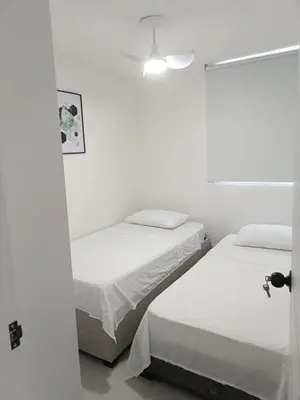 two beds in a room with white walls at Apartamento en Cartagena amoblado con vista al mar in Cartagena de Indias