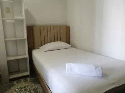 a small bedroom with a white bed and shelves at Cómodo APTO En El Laguito las 3 Carabelas in Cartagena de Indias