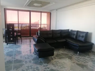 a living room with a black leather couch and stool at Cómodo APTO En El Laguito las 3 Carabelas in Cartagena de Indias