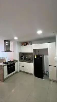 a kitchen with white cabinets and a black refrigerator at Apartamento en Cartagena Marbella in Cartagena de Indias