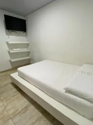 a white bedroom with a bed and a tv at Hotel Nellamar in Puerto Colombia