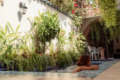 a woman sitting in a swimming pool next to a house at Casa Heredia Boutique in Cartagena de Indias