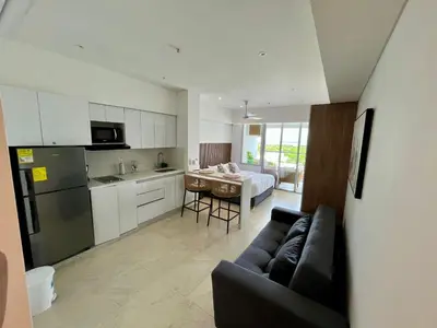 a living room with a black couch and a kitchen at cartagena beach resort in Cartagena de Indias