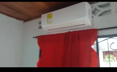 a air conditioner hanging from a ceiling with a red curtain at Hospedaje el floral in Tolú