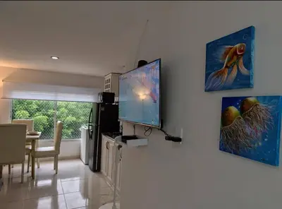a living room with a television and a dining room at Apartamento en Cielo Mar in Cartagena de Indias