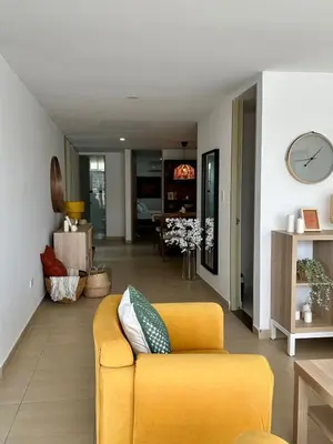 a living room with a yellow couch and a clock at Apto Familiar Moderno Cerca de Todo en Coveñas in Coveñas