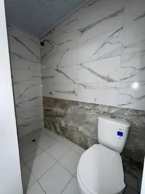 a bathroom with a white toilet and a marble wall at Orilla beach house in Playa Punta Arena