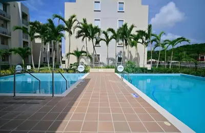 a swimming pool with palm trees and a building at Apartamento Cartagena Tranquilo playa-piscina in Manzanillo del Mar