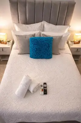 a bed with white pillows and two remote controls on it at Apartaestudio Económico a una cuadra de la Playa in Cartagena de Indias