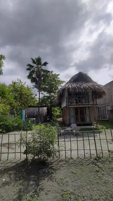 a building with a straw hut with a palm tree at CARPE DIEM oceanfront cabin private beach in San Bernardo del Viento