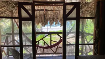 a window view of a hammock from a hut at CARPE DIEM oceanfront cabin private beach in San Bernardo del Viento