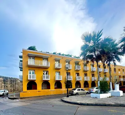 a yellow building with a palm tree in front of it at Cozy duplex at Cartagena City Center in Cartagena de Indias