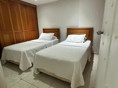 two beds in a room with white linens at Lujoso apartamento frente al Castillo de San Felipe in Cartagena de Indias