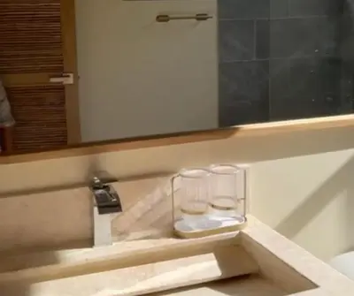 a glass holder on a bathroom sink with a mirror at Casa Azure Playas del Francés in El Puertón
