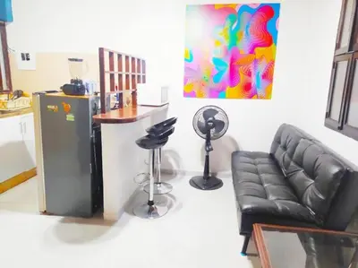 a living room with a black leather couch and a kitchen at tranquilo alojamiento centro cartagena in Cartagena de Indias