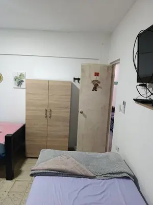 a bedroom with a bed and two wooden cabinets at Hostal Mastcoy in Cartagena de Indias