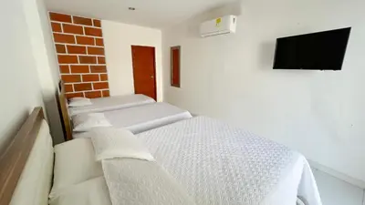 a room with two beds and a tv on a wall at Hotel Zoe in Sampués