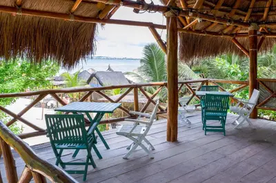 a table and chairs on a deck with a view of the beach at Cabaña privada con Jacuzzi a solo un minuto de la playa in Isla de Tierra Bomba