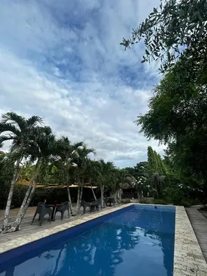 a blue swimming pool with chairs and palm trees at Cabaña privada con Jacuzzi a solo un minuto de la playa in Isla de Tierra Bomba