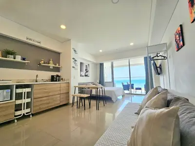 a living room with a couch and a kitchen with a table at Apartasuit Resort CTG Beach con vista al mar- central 5 min aeropuerto in Cartagena de Indias