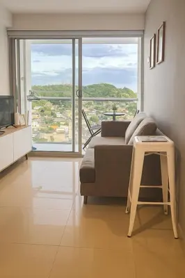 a living room with a couch and a large window at Oasis Costero Apartment in Cartagena de Indias