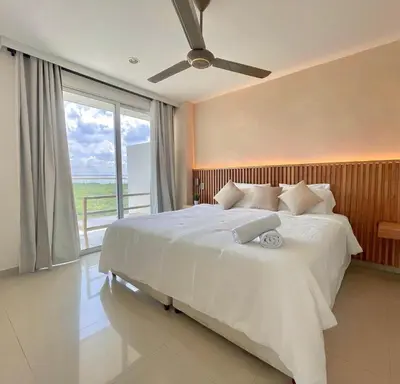 a bedroom with a large white bed with a large window at Luxury apartment sea view with pool- central 12 min from the city center in Cartagena de Indias