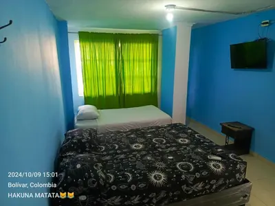 a bedroom with a bed and a window with a green curtain at Hospedaje Bosque Mar in Cartagena de Indias