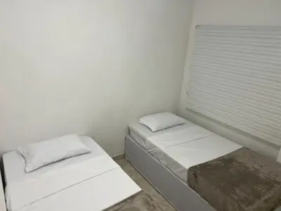 two beds in a white room with a window at Cartagena Visible Hostal in Cartagena de Indias