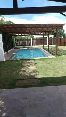 a swimming pool in a yard with a wooden pergola at Casa 550 in Turbaco