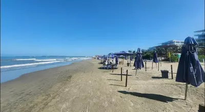 an empty beach with umbrellas and the ocean at apartment near the beach con piscina, gym y coworking in Manzanillo del Mar