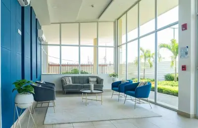 a living room with blue chairs and a couch at apartment near the beach con piscina, gym y coworking in Manzanillo del Mar