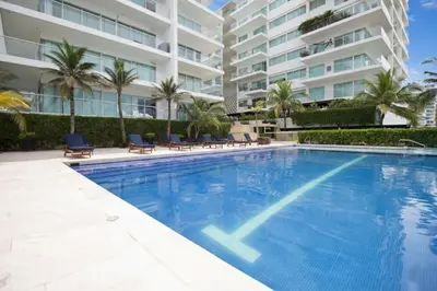 a swimming pool with chairs and a large building at Morros Flamingo Suite - con vista al mar y acceso a la playa in Cartagena de Indias