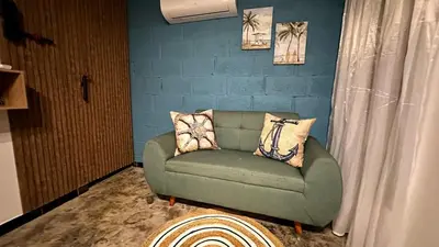 a green couch in a room with a blue wall at Cabaña Coveñas Tolú in Coveñas