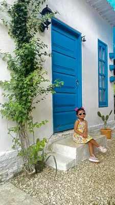 a little girl sitting on a step in front of a door at Cabaña Coveñas Tolú in Coveñas