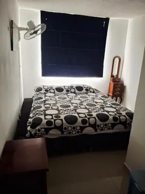 a bed with a black and white comforter in a room at APARTAMENTO-Miramar in Barranquilla