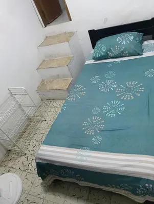 a bed with a green comforter and pillows at Habitación con medio baño en el barrio ciudad jardín Barranquilla in Barranquilla