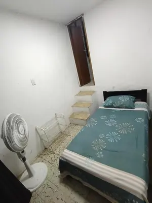 a bedroom with a bed with a fan and stairs at Habitación con medio baño en el barrio ciudad jardín Barranquilla in Barranquilla