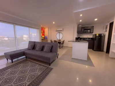 a living room with a couch and a kitchen at Stunning Caribbean-Inspired PH next to Viva Mall in Barranquilla