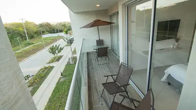 a balcony with two chairs and a bed and a bedroom at Exclusive New 1-BR Apartment in Baia Kristal Kabo in Los Arrayanes