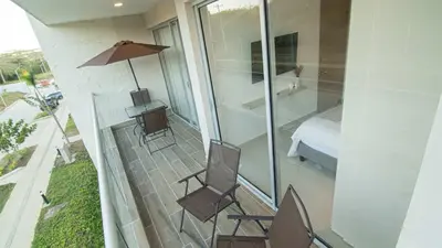 a balcony with two chairs and a table and a bed at Exclusive New 1-BR Apartment in Baia Kristal Kabo in Los Arrayanes