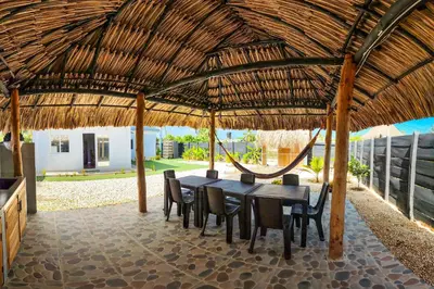a wooden table and chairs under a straw roof at Villa Martina in Moñitos