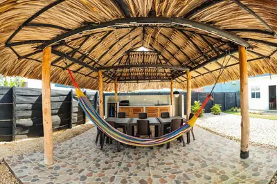 a hammock in a pavilion with a table and chairs at Villa Martina in Moñitos