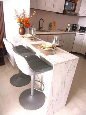 a kitchen with a large white counter with chairs and glasses at Magica Cartagena Suite in Cartagena de Indias