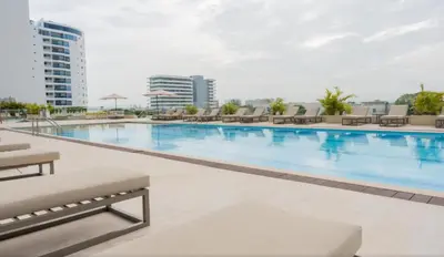 a large swimming pool with chairs and a building at Relax vista al mar Aparta suite in Cartagena de Indias