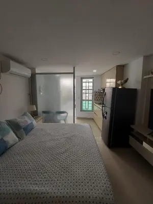 a bedroom with a large bed and a refrigerator at Apartaestudio al frente del Mar in Cartagena de Indias
