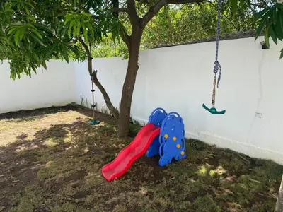 a childs play set next to a tree with a swing at Private pool cabin near the sea Puerto Velero in Tubará
