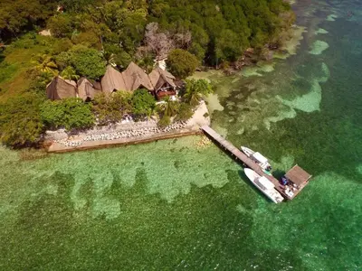 an island with a house and a boat in the water at Accommodation on a coral island with turquoise sea in Cartagena de Indias