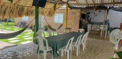a table with white chairs and a green table and a kitchen at CABAÑA el EDEN in Santa Veronica