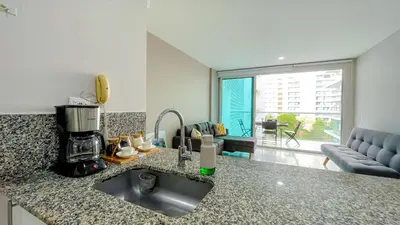 a kitchen counter with a sink and a living room at Comodos Aptos en Morros3 con salida directa a la playa, piscina & parking in Cartagena de Indias