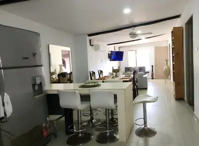 a kitchen and living room with a counter and stools at Casa playa salgar in Puerto Colombia